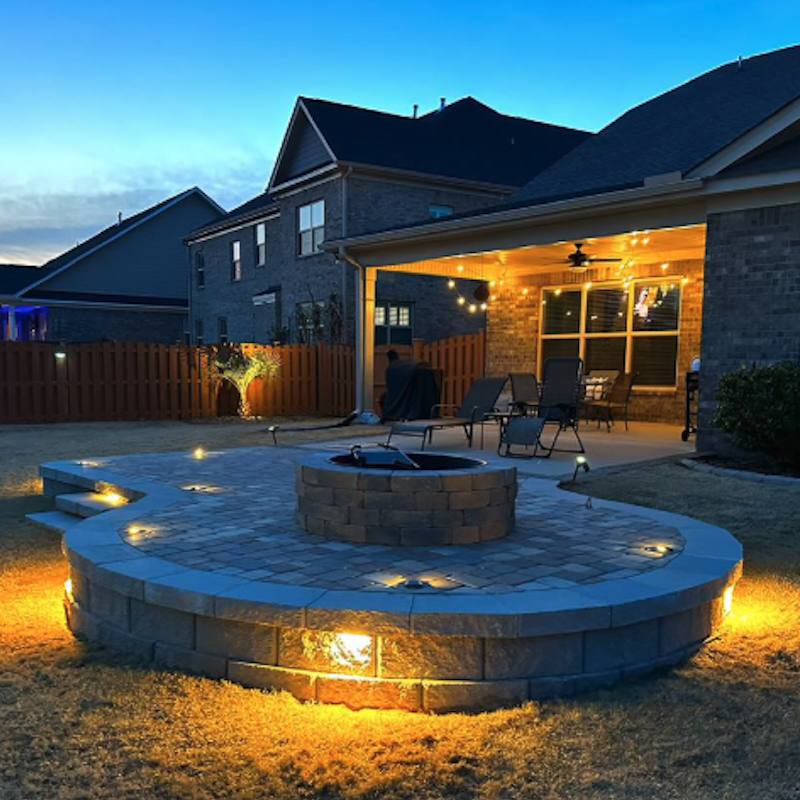 Backyard fire pit with glowing landscape lighting